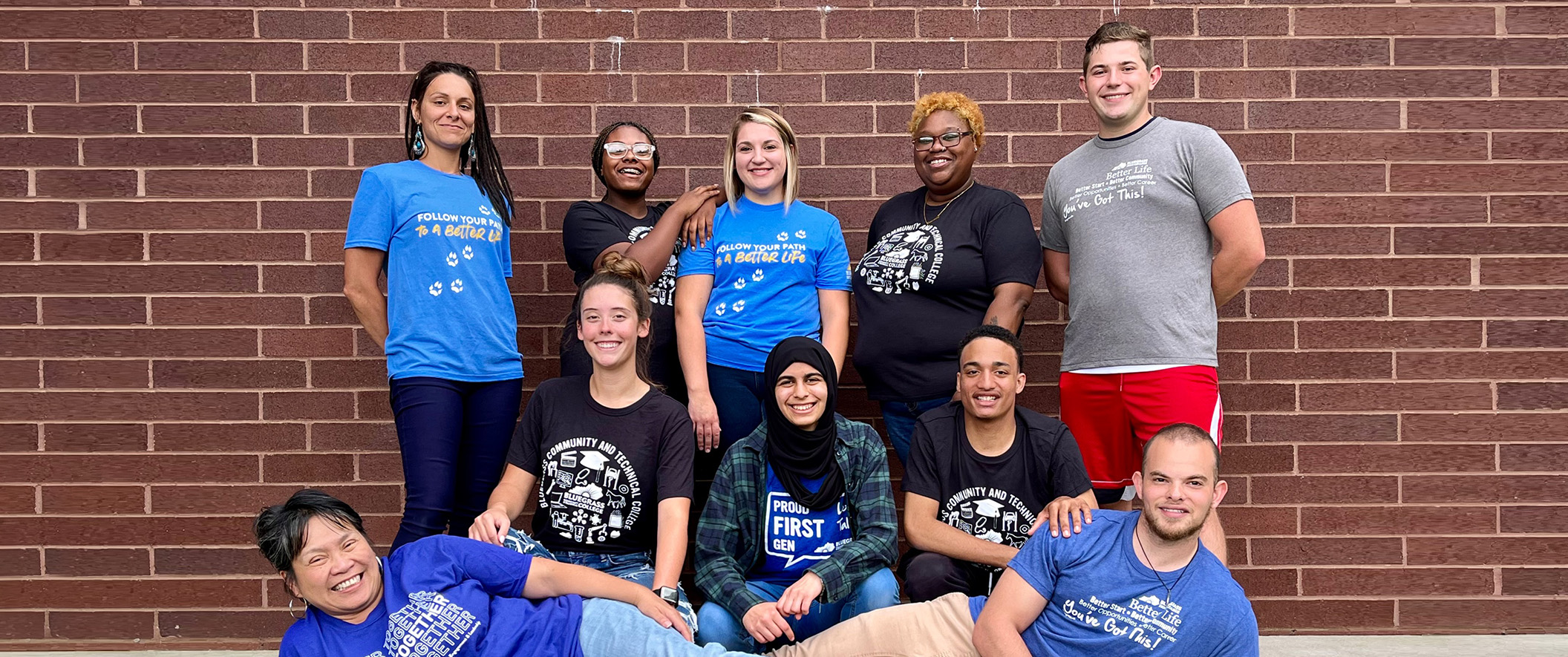 group of students posed in front of brick wall